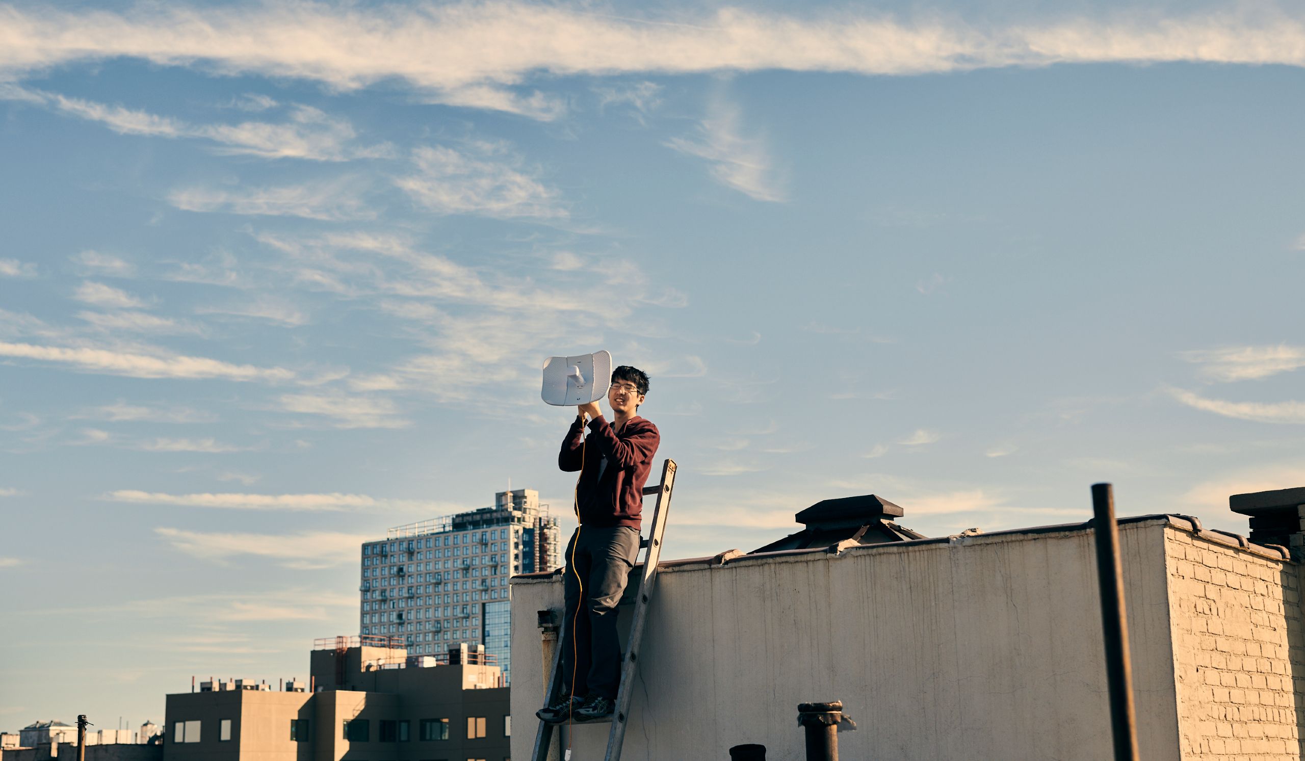 Man installing an internet node on a rooftop